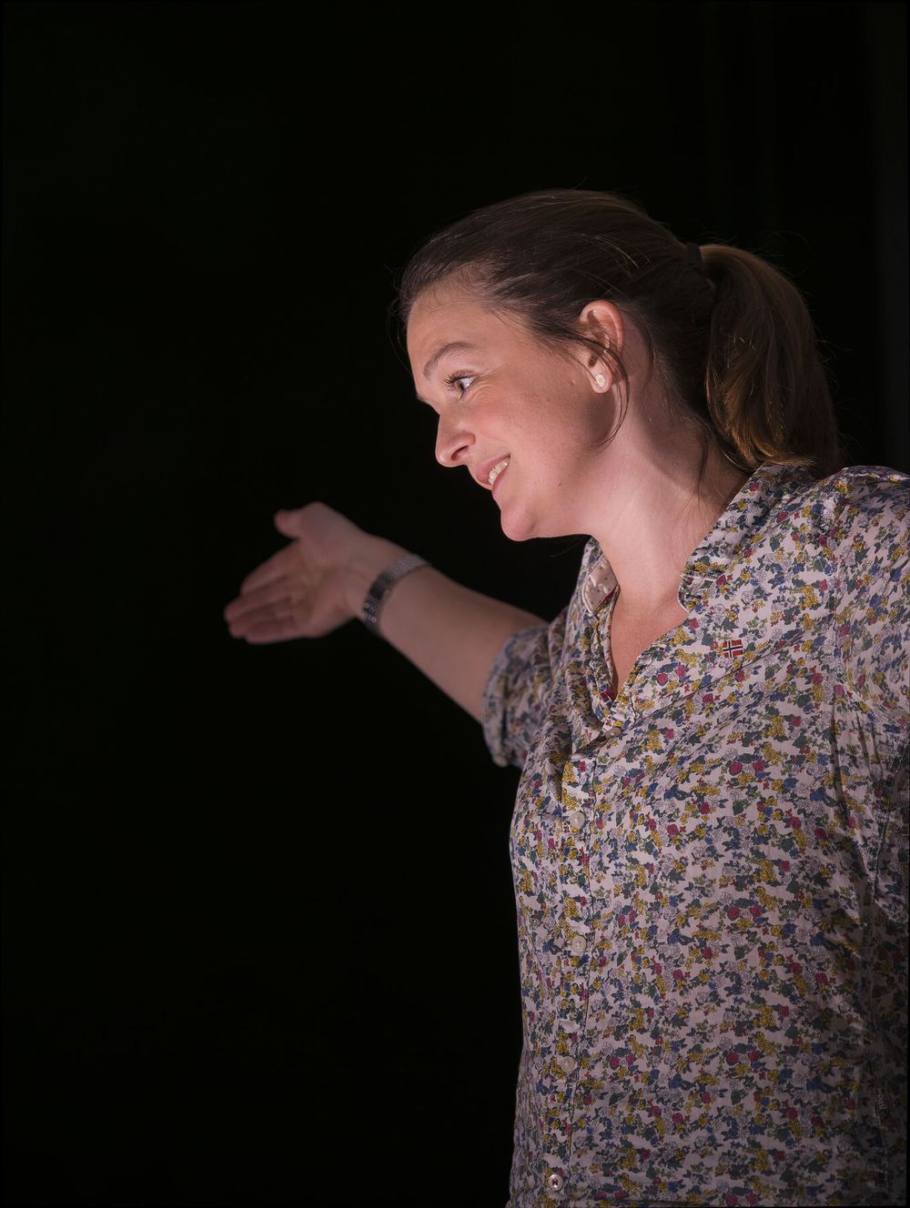 Sybille Montagne, sourire aux lèvres, tend la main vers le public pendant le seule-en-scène